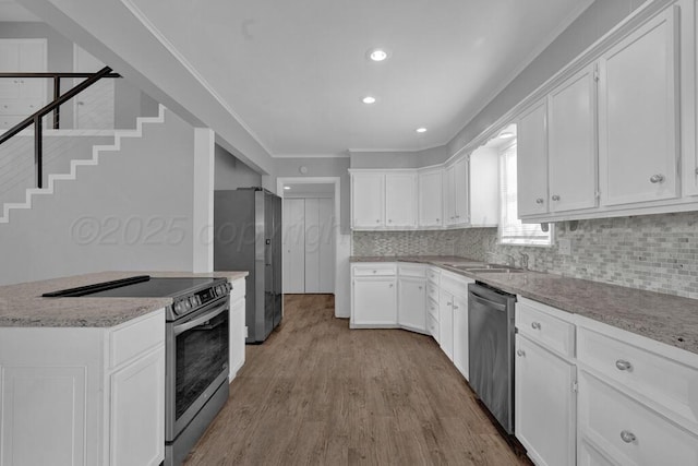 3700 Paramount Blvd, Amarillo, TX 79109 - kitchen featuring stainless steel appliances, wood finished floors, white cabinetry, tasteful backsplash, and crown molding