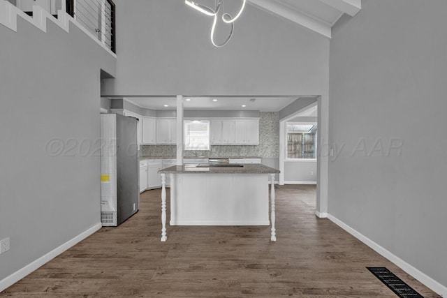 3700 Paramount Blvd, Amarillo, TX 79109 - kitchen with refrigerator, white cabinetry, a kitchen island, high vaulted ceiling, and dark wood finished floors
