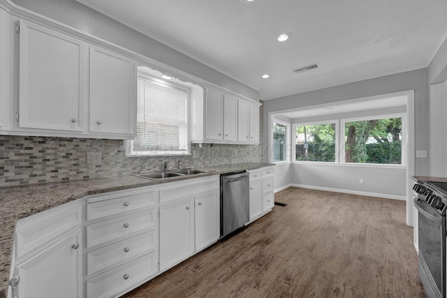 3700 Paramount Blvd, Amarillo, TX 79109 - kitchen featuring appliances with stainless steel finishes, white cabinetry, wood finished floors, decorative backsplash, and ornamental molding