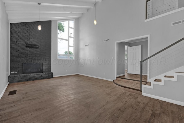 3700 Paramount Blvd, Amarillo, TX 79109 - unfurnished living room with healthy amount of natural light, wood finished floors, a fireplace, high vaulted ceiling, and beamed ceiling