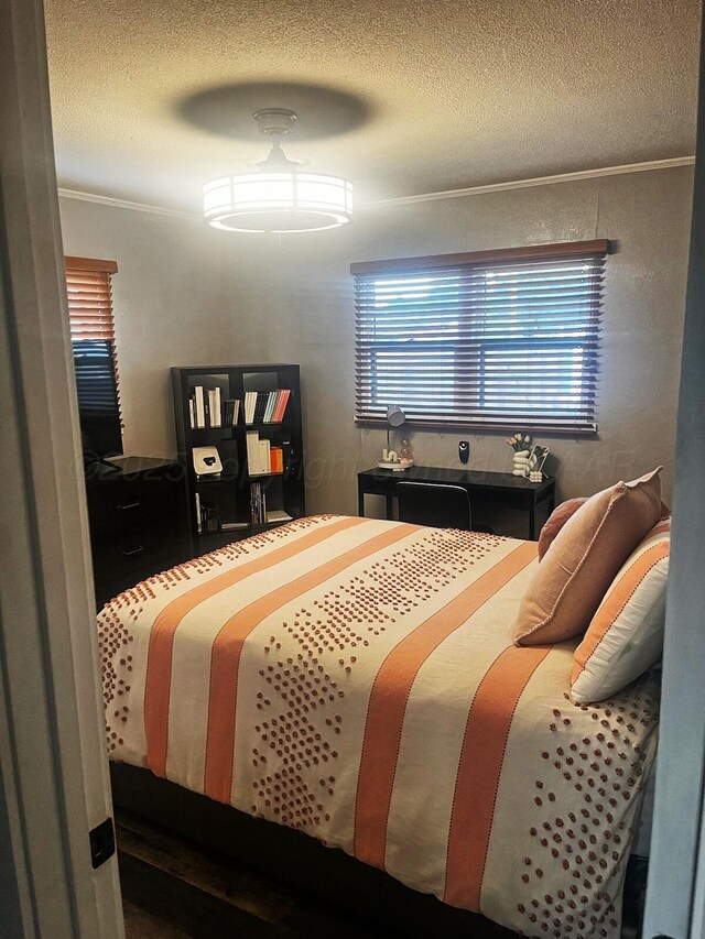 bedroom with ceiling fan, crown molding, and a textured ceiling