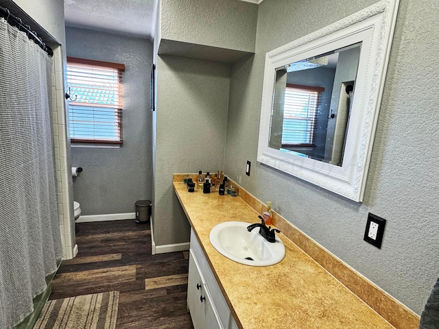 bathroom featuring hardwood / wood-style flooring, vanity, a wealth of natural light, and toilet