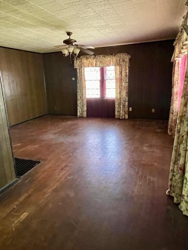 unfurnished room with ceiling fan and wooden walls