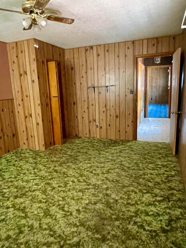 spare room featuring ceiling fan, a textured ceiling, and wooden walls