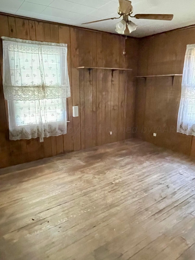 spare room with wood walls, ceiling fan, and light hardwood / wood-style floors