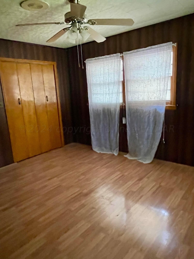 unfurnished bedroom with ceiling fan, a closet, and wood-type flooring