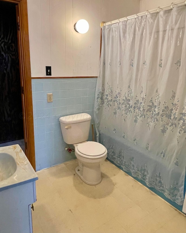 full bathroom with vanity, toilet, tile walls, and shower / bath combo with shower curtain