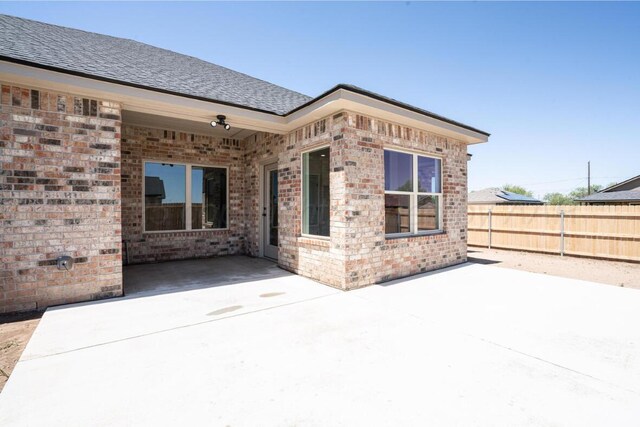 719 Prairie Ave, Dumas, TX 79029 - rear view of property with a patio area, fence, brick siding, and a shingled roof