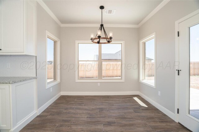 719 Prairie Ave, Dumas, TX 79029 - unfurnished dining area featuring a chandelier, dark wood-style flooring, crown molding, and baseboards