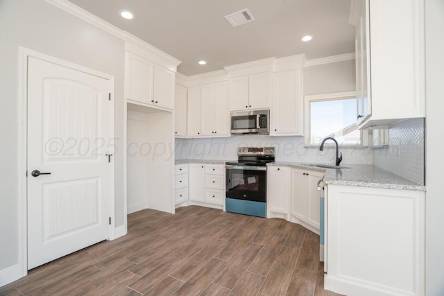 719 Prairie Ave, Dumas, TX 79029 - kitchen with stainless steel appliances, a sink, light stone counters, white cabinetry, and crown molding