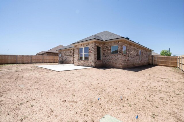 719 Prairie Ave, Dumas, TX 79029 - back of house featuring a patio area, brick siding, a fenced backyard, and central AC