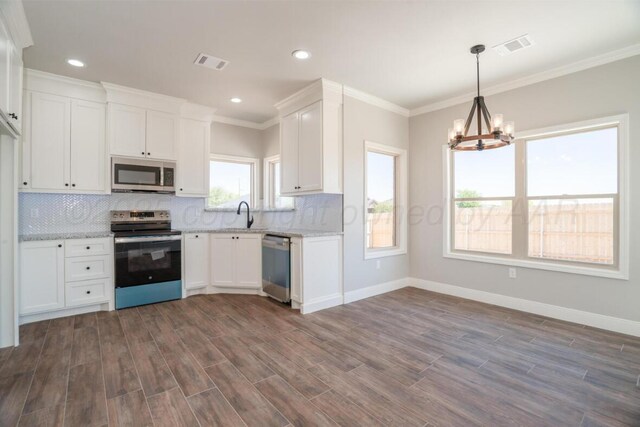 719 Prairie Ave, Dumas, TX 79029 - kitchen featuring stainless steel appliances, a chandelier, backsplash, white cabinets, and ornamental molding
