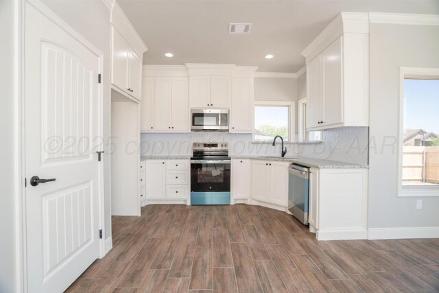 719 Prairie Ave, Dumas, TX 79029 - kitchen with appliances with stainless steel finishes, white cabinetry, dark wood-style flooring, tasteful backsplash, and recessed lighting
