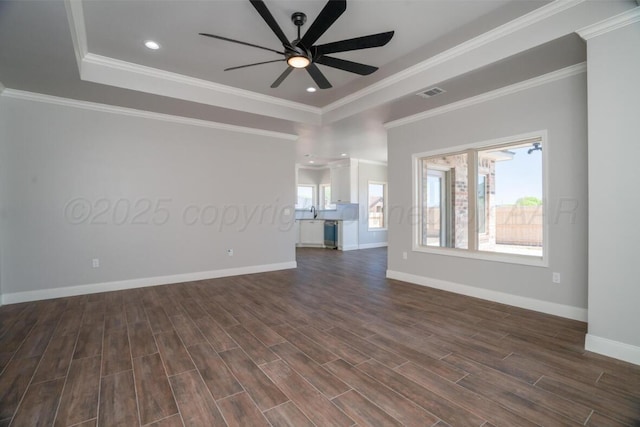 719 Prairie Ave, Dumas, TX 79029 - unfurnished room featuring a ceiling fan, dark wood-style floors, baseboards, a tray ceiling, and ornamental molding