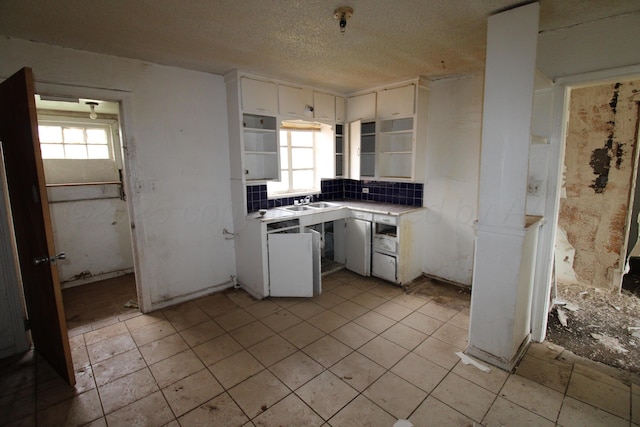 kitchen with open shelves, white cabinets, light countertops, a sink, and light tile patterned floors