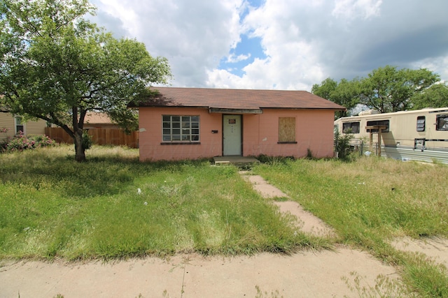 view of front of home featuring concrete block siding and fence
