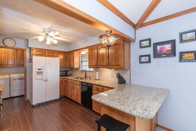 7919 Mitcham Dr, Amarillo, TX 79121 - kitchen featuring black appliances, separate washer and dryer, a peninsula, brown cabinets, and lofted ceiling