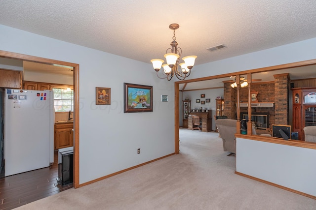 7919 Mitcham Dr, Amarillo, TX 79121 - unfurnished living room featuring a chandelier, a brick fireplace, a textured ceiling, and light carpet