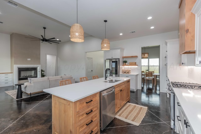 kitchen featuring appliances with stainless steel finishes, sink, white cabinets, ceiling fan, and a kitchen island with sink