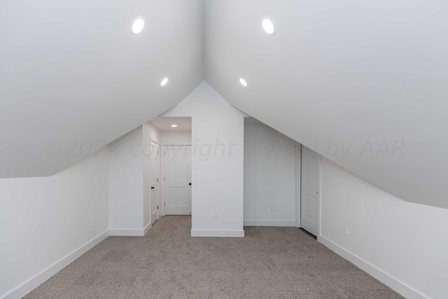 additional living space featuring light colored carpet and lofted ceiling