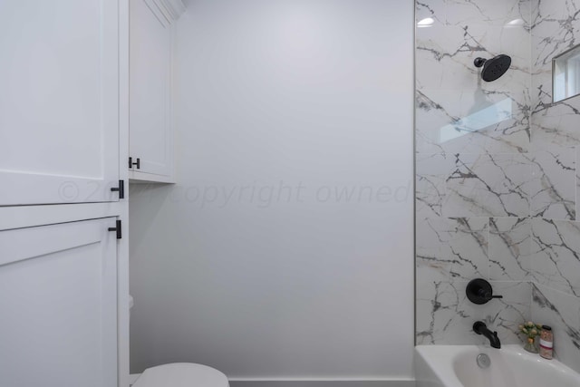 bathroom featuring toilet and tiled shower / bath