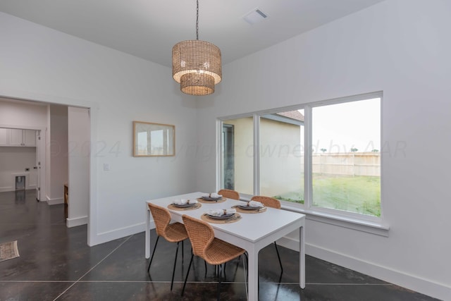dining room with dark tile patterned flooring and an inviting chandelier