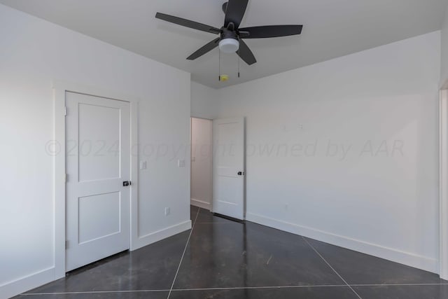 unfurnished bedroom featuring dark tile patterned flooring and ceiling fan