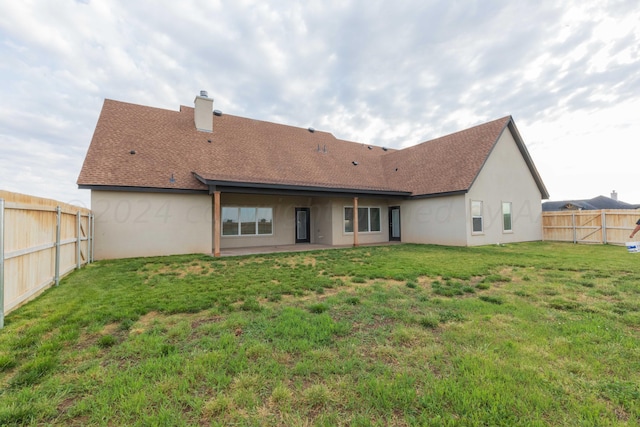 rear view of house with a patio and a yard