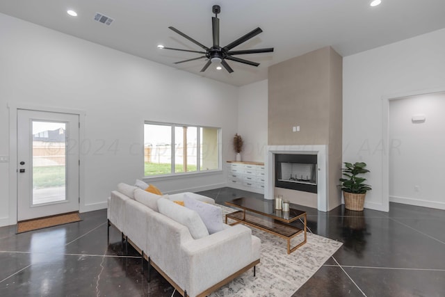 living room featuring a towering ceiling, ceiling fan, and a healthy amount of sunlight