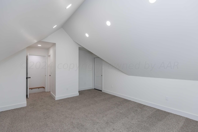 additional living space featuring light colored carpet and lofted ceiling