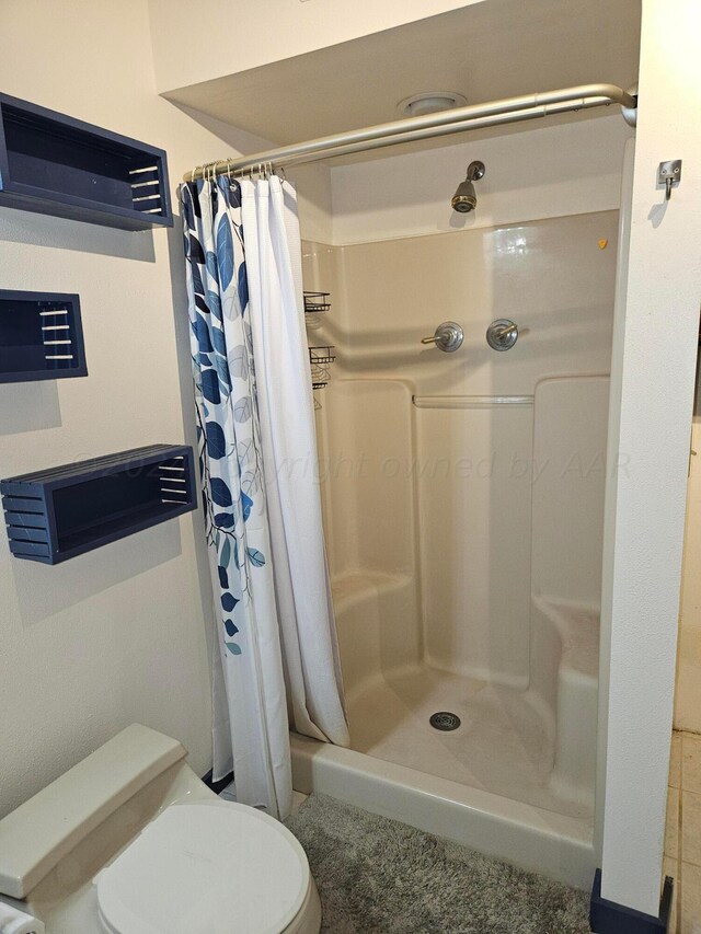 bathroom featuring a shower with shower curtain, tile patterned flooring, and toilet