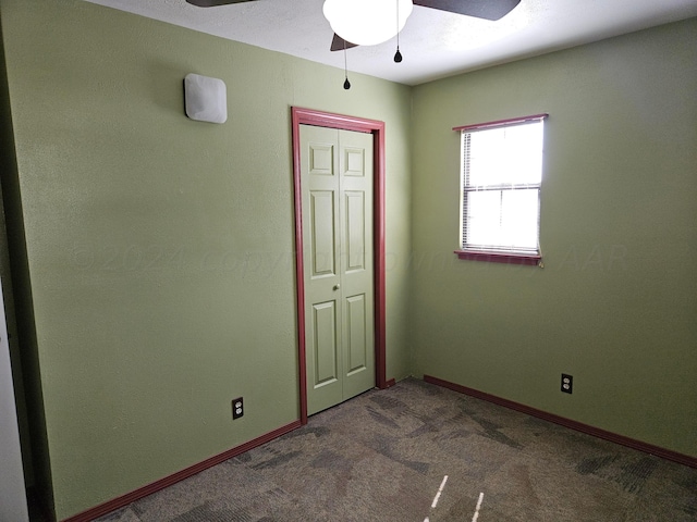 unfurnished room with dark colored carpet and ceiling fan