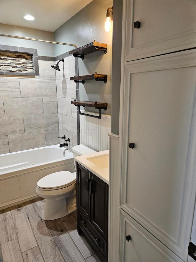 full bathroom featuring toilet, tiled shower / bath combo, vanity, and hardwood / wood-style floors