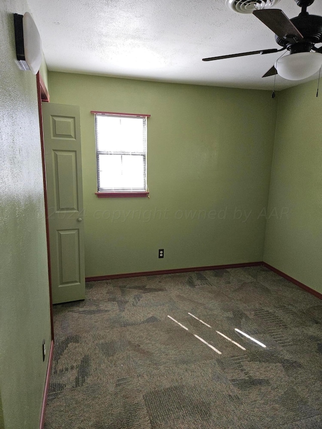 carpeted spare room featuring ceiling fan and a textured ceiling