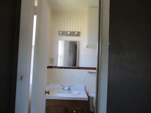 1502 Lancelot St, Borger, TX 79007 - bathroom with vanity, tile walls, toilet, and a wainscoted wall