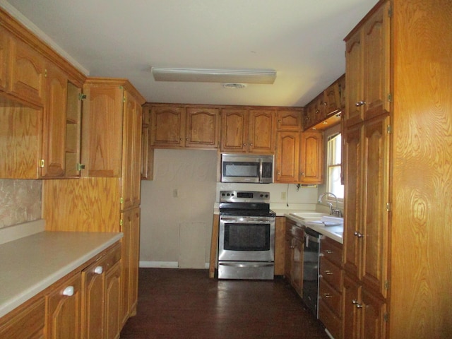 1502 Lancelot St, Borger, TX 79007 - kitchen with appliances with stainless steel finishes, a sink, brown cabinetry, and light countertops