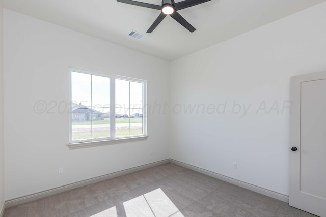 spare room with light colored carpet, baseboards, a ceiling fan, and visible vents