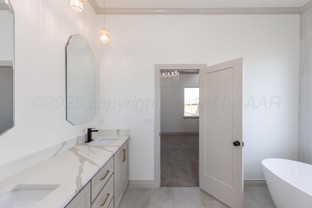 bathroom with double vanity, a sink, baseboards, a freestanding tub, and a notable chandelier