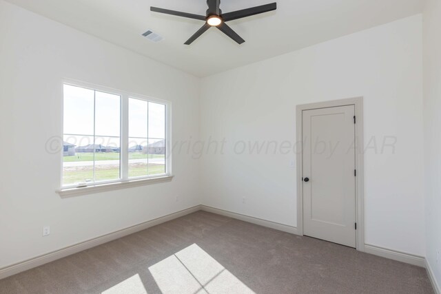 carpeted empty room with baseboards, a ceiling fan, and visible vents