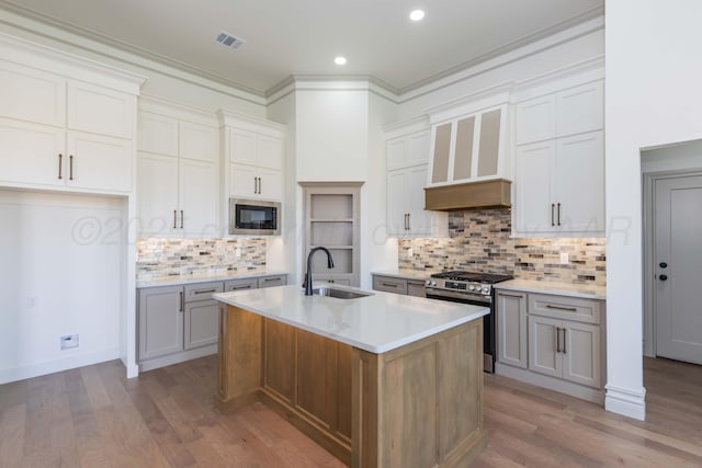 kitchen featuring stainless steel range with gas cooktop, a sink, built in microwave, decorative backsplash, and visible vents