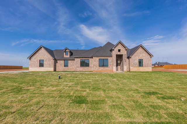 view of front facade with brick siding, roof with shingles, and a front lawn