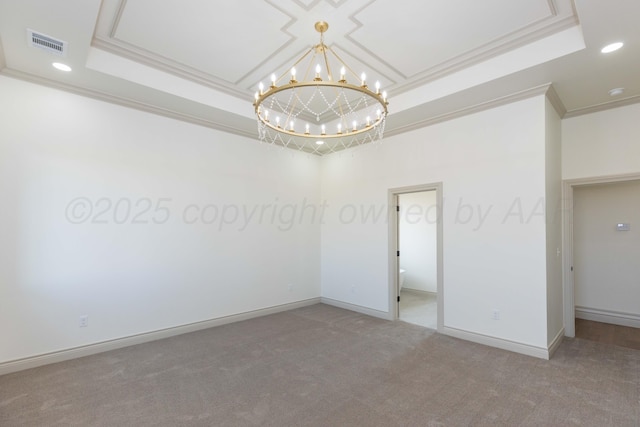spare room with carpet floors, a notable chandelier, a tray ceiling, and visible vents