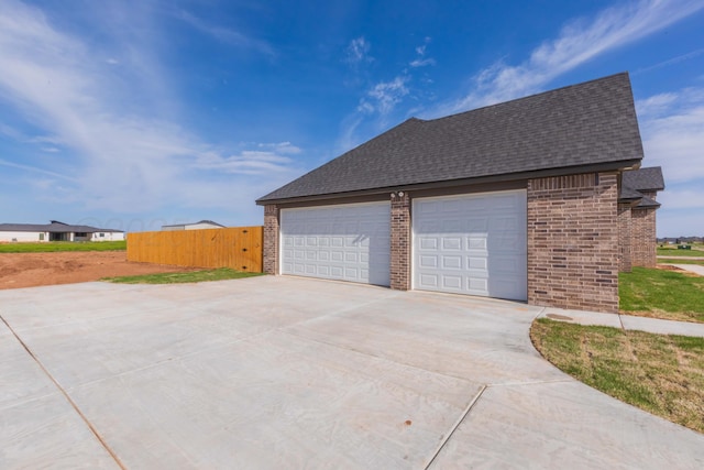 garage with concrete driveway and fence
