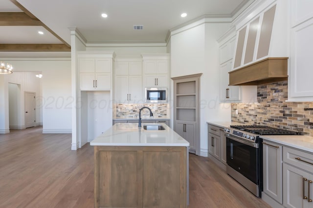 kitchen with wood finished floors, a sink, light countertops, custom range hood, and appliances with stainless steel finishes