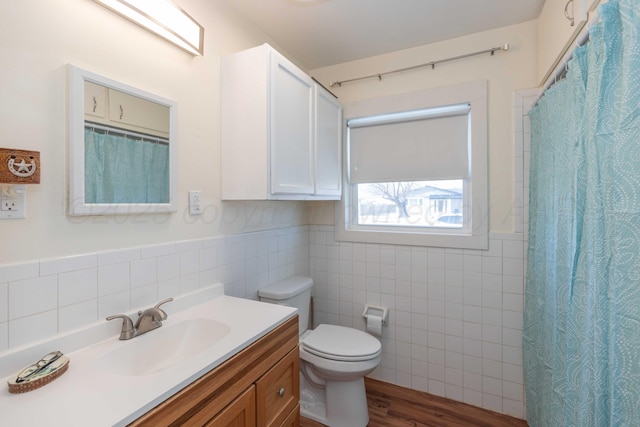 full bath featuring curtained shower, toilet, wood finished floors, vanity, and tile walls