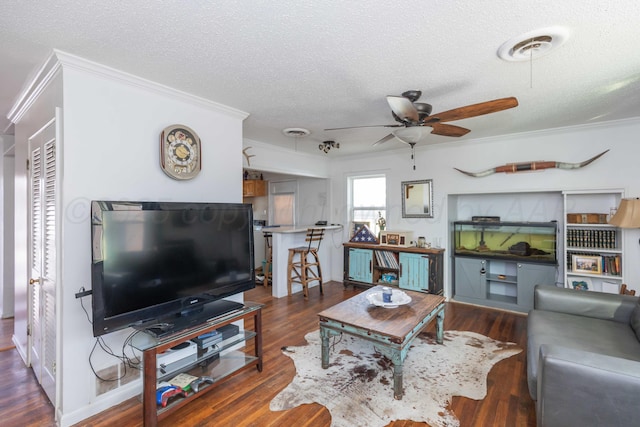 living room with dark wood-style floors, visible vents, ornamental molding, and a textured ceiling