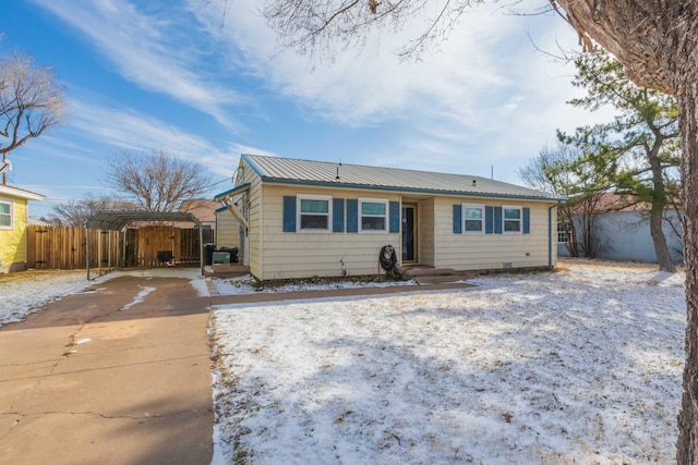 ranch-style house featuring metal roof, fence, and driveway