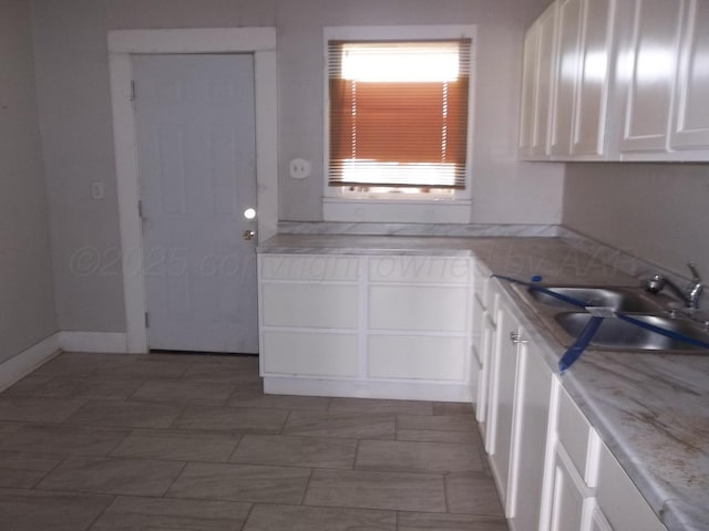 kitchen with light countertops, a sink, and white cabinetry