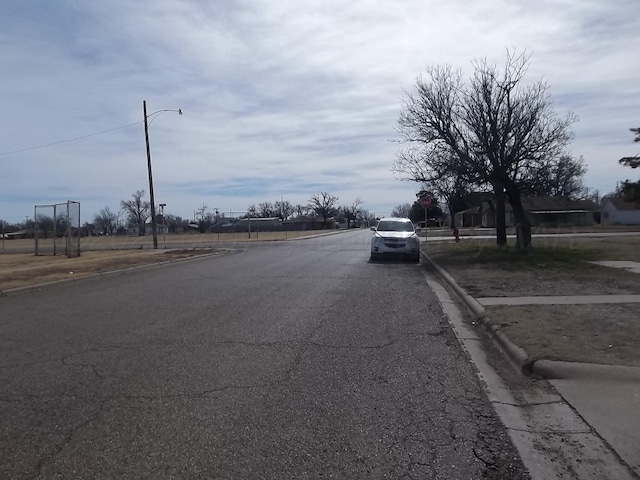 view of street featuring street lighting, traffic signs, and curbs