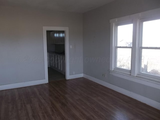 unfurnished room featuring dark wood-style flooring and baseboards